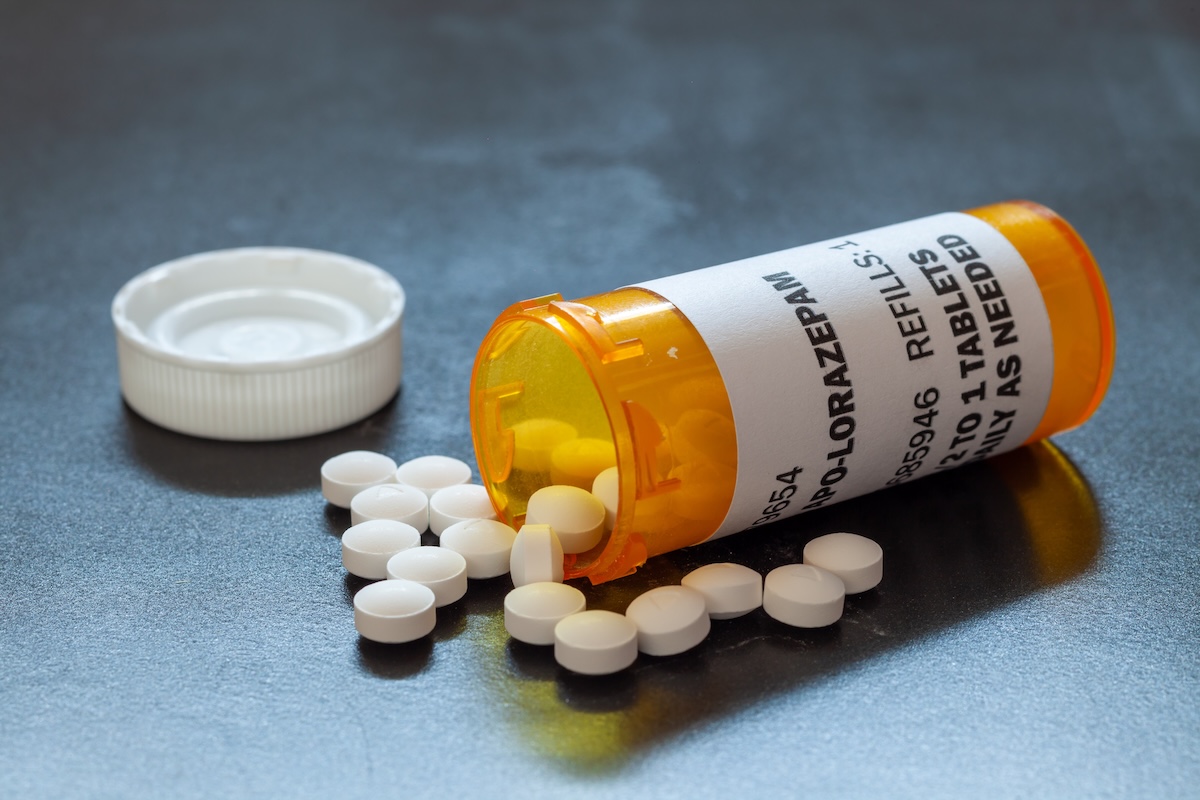 Orange pill container on its side with white pills spilling out