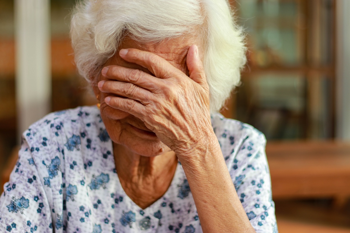 Woman with white hair has hand in front of face