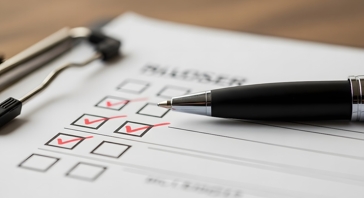 White paper on a clipboard with survey boxes and red checkmarks and a pen on top